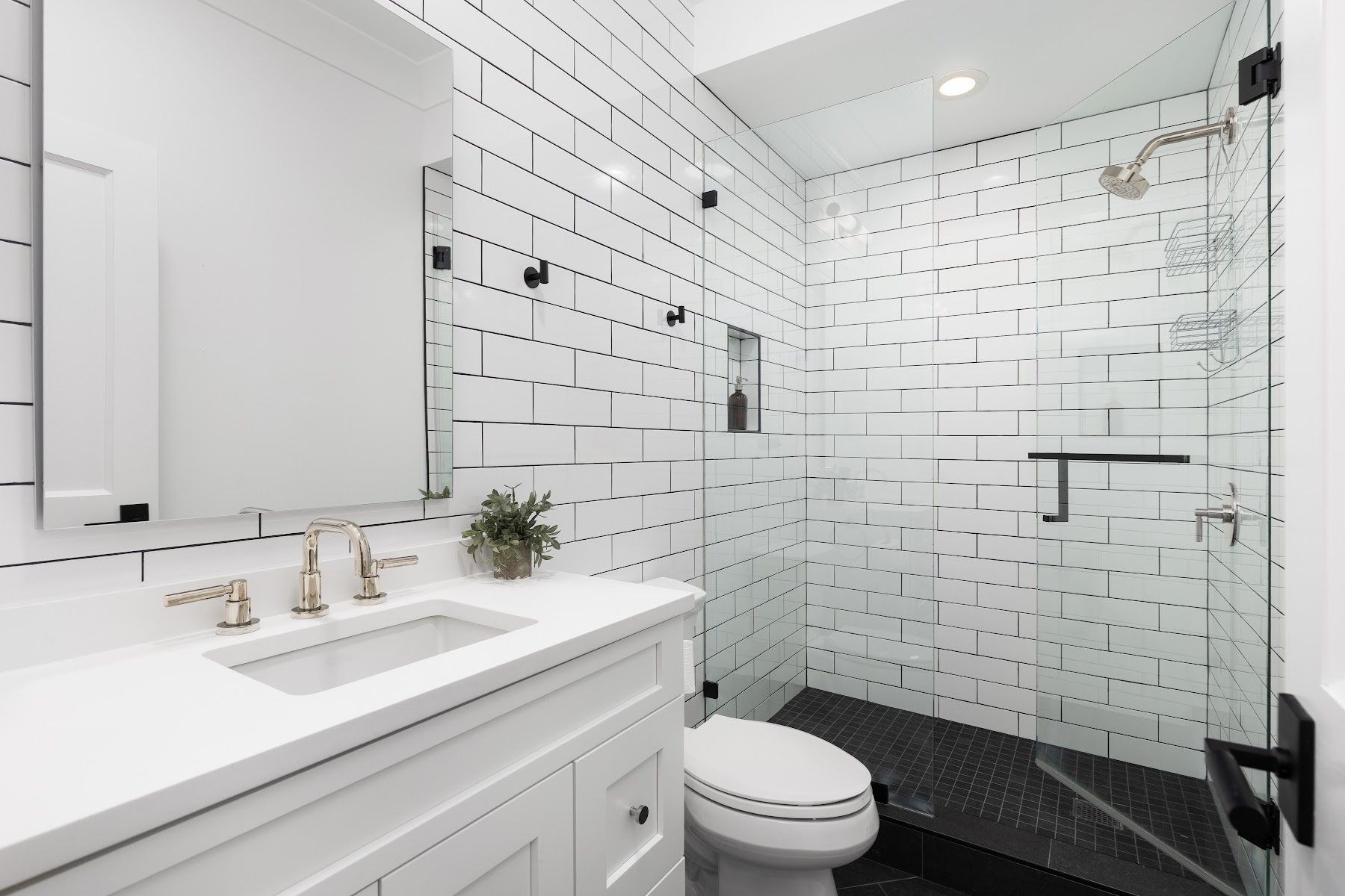 White tiled bathroom with a bathtub, shower, and glass screen