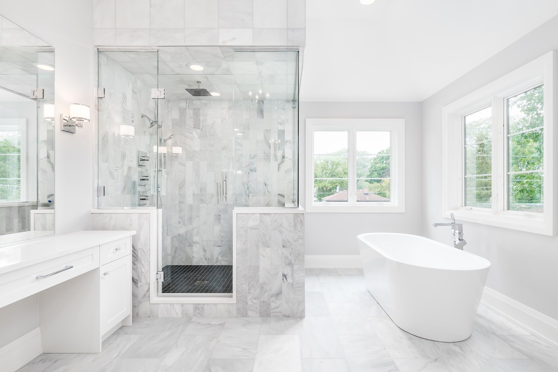 Bright bathroom with freestanding tub, glass shower, and marble-look tile