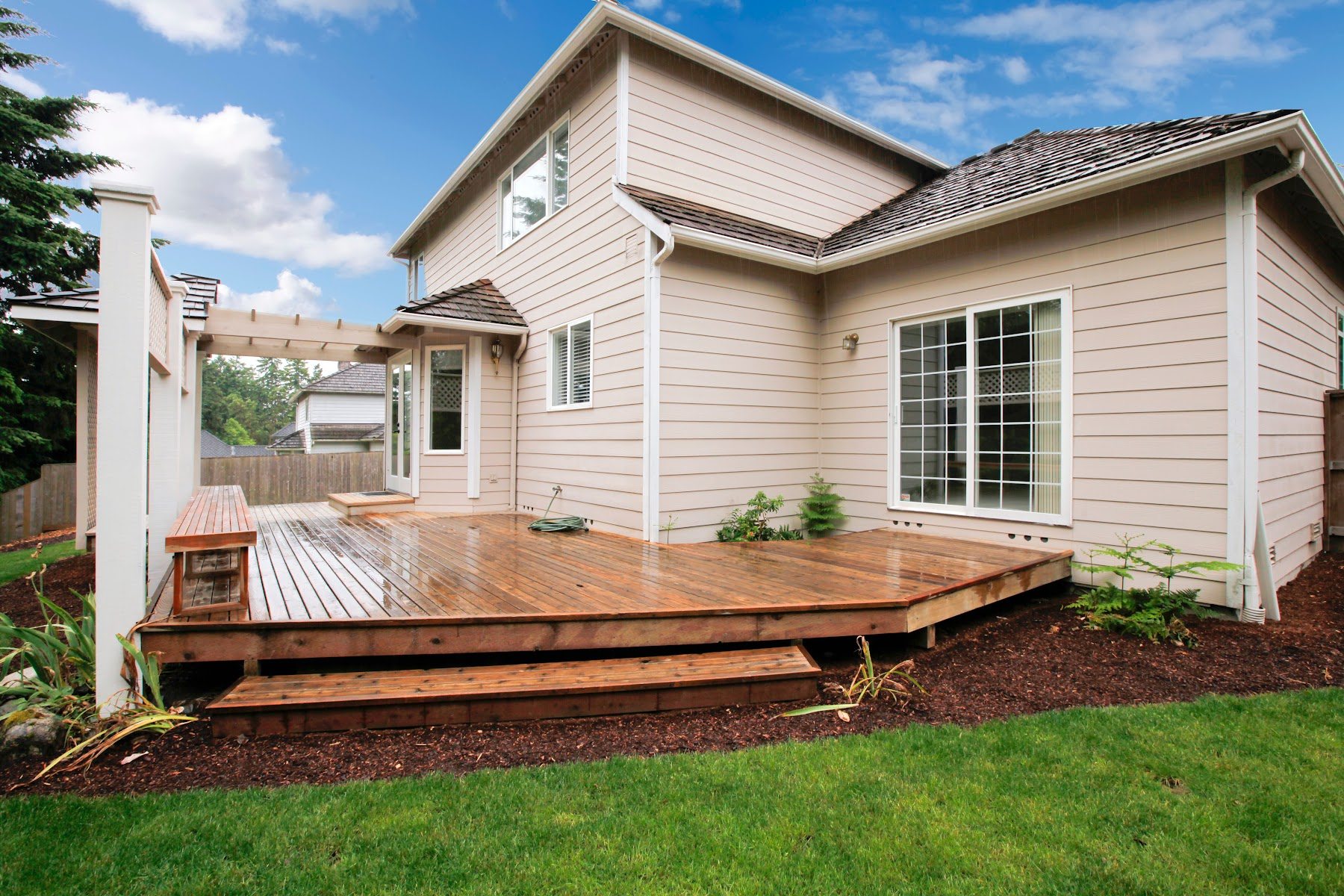 Ground-level wood deck wrapping around a residential addition
