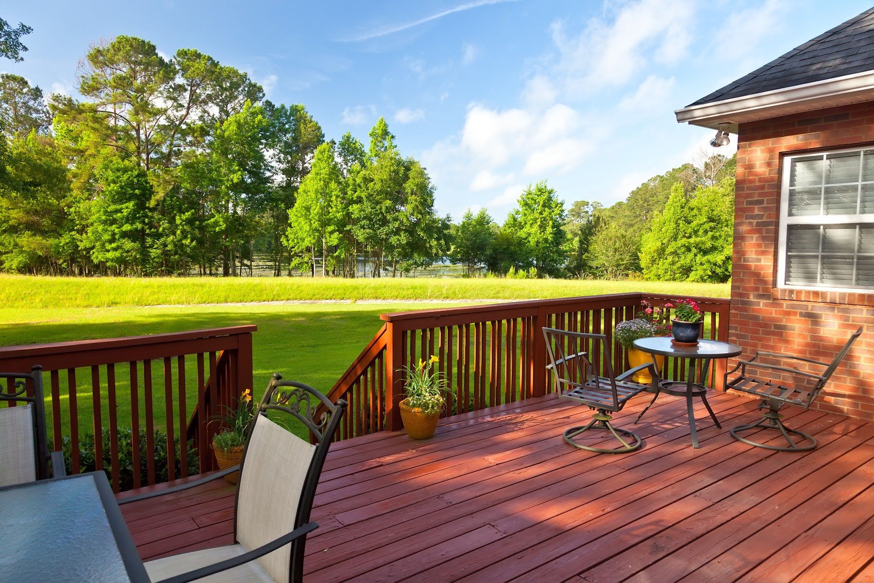 Elevated backyard deck with railing and tree-lined views