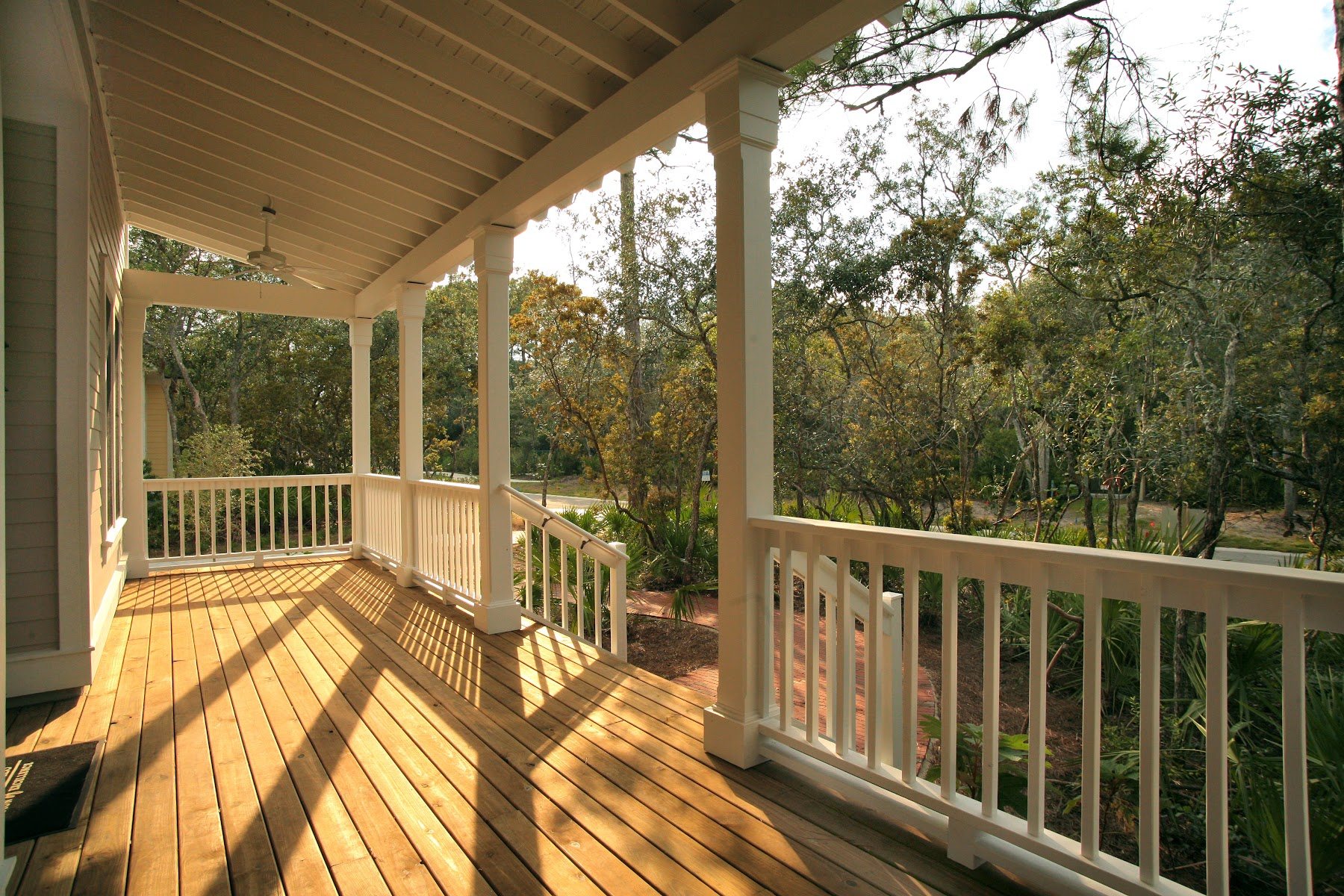 Covered wood deck with white railing overlooking mature trees
