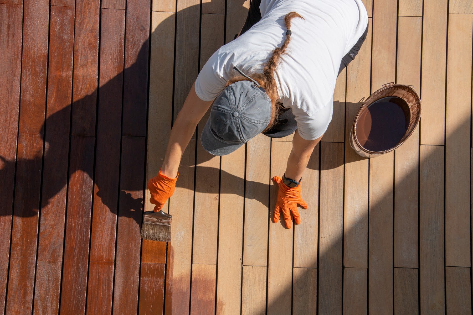 Deck boards being stained by hand with a brush
