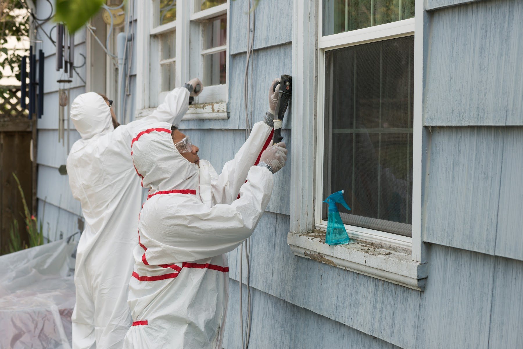 Painters preparing and coating weathered exterior wood siding