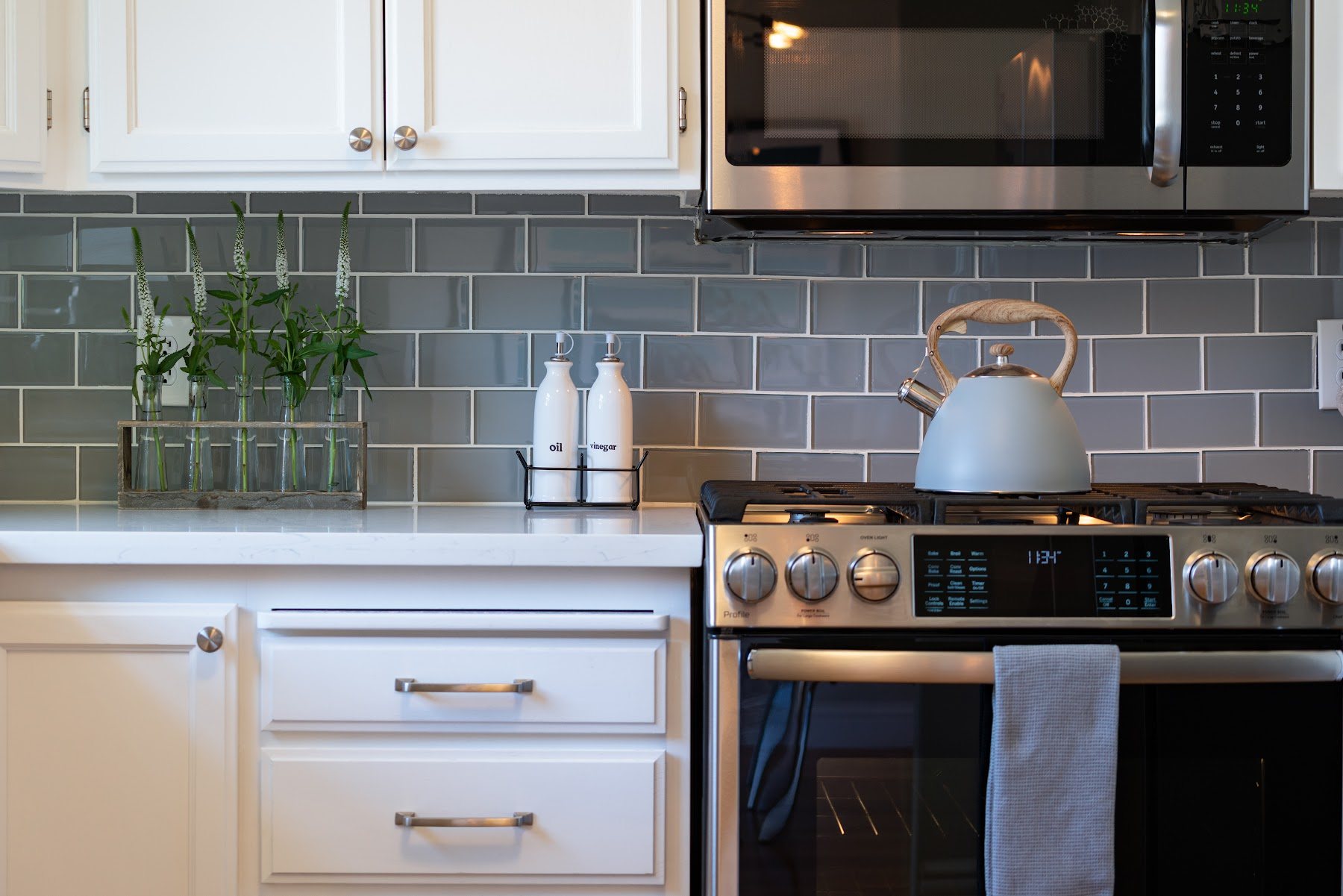 Kitchen with mixed dark and light cabinetry and a green tile backsplash
