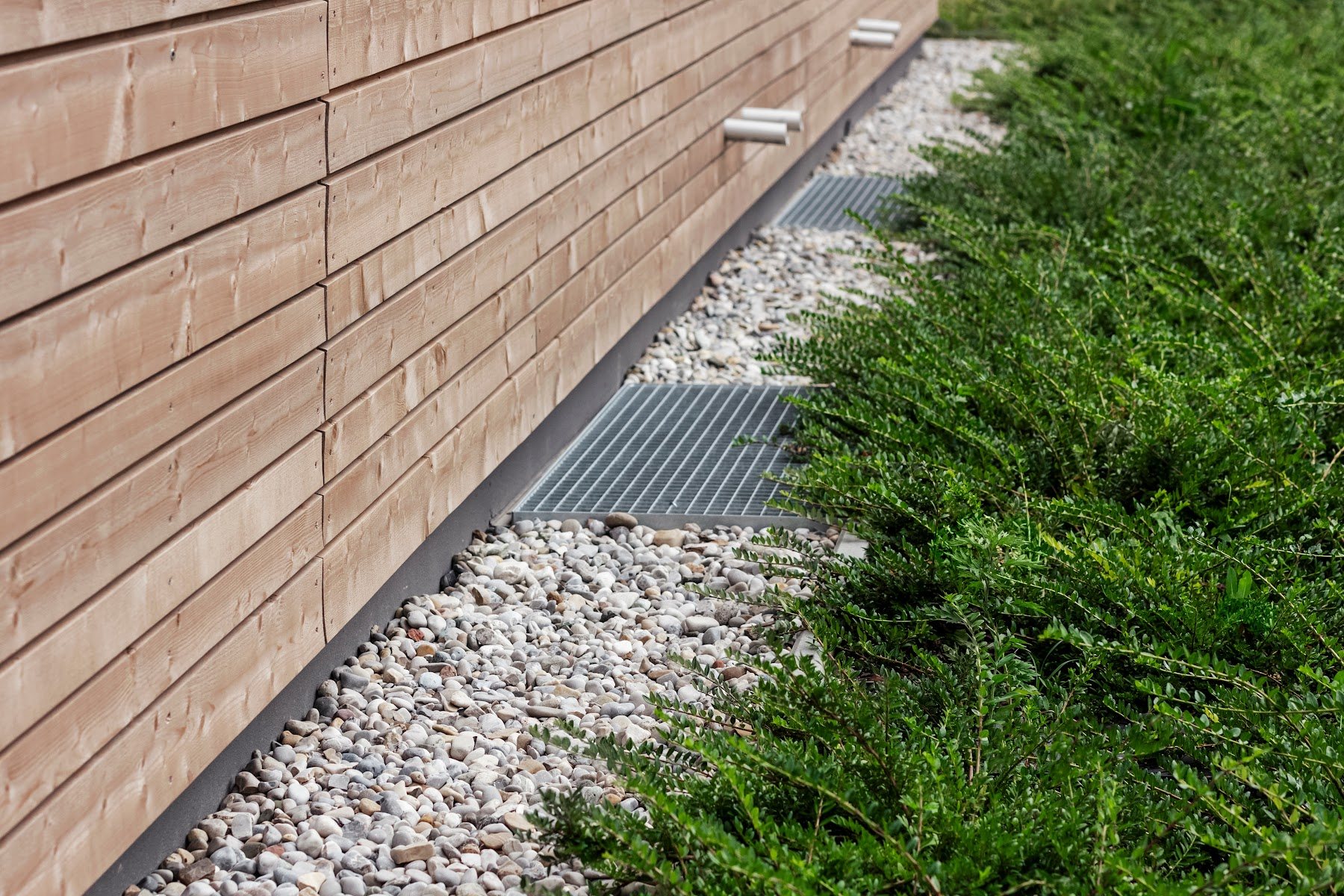 Perimeter drainage detail beside wood siding and landscaping
