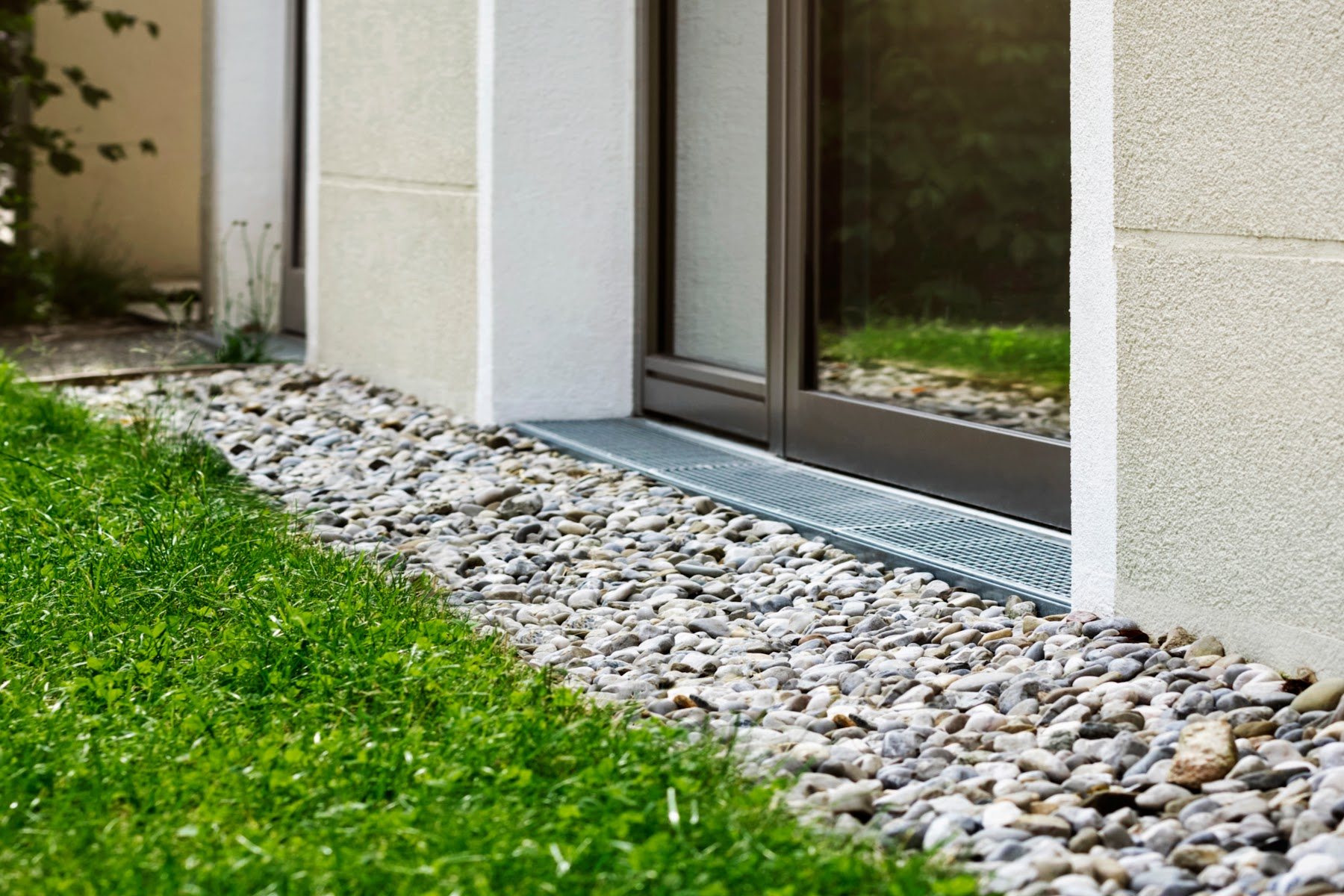 Exterior foundation drainage and gravel installed beside a patio door