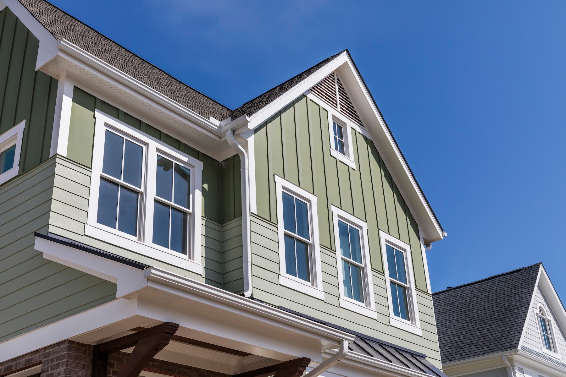 Green lap siding with white window trim and gable details